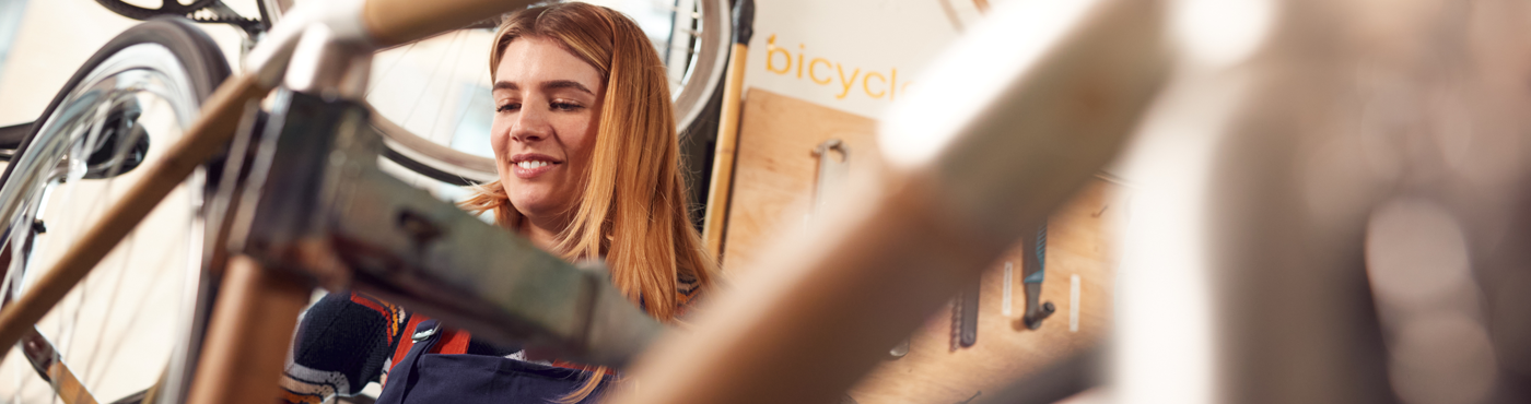 Eine Auszubildende montiert lächelnd ein Fahrrad und ist dabei von anderen Rädern umgeben.